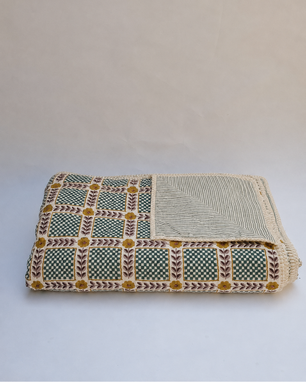 A folded woven textile, likely a Japanese yukata or blanket, featuring a green and beige patterned side with yellow geometric accents and a solid beige striped reverse side, set against a plain light background.