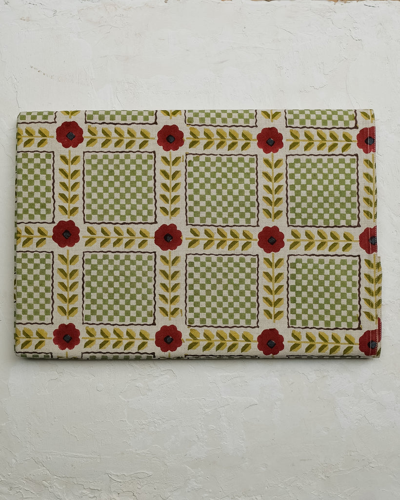 Small rectangular fabric sample with floral and checkered pattern on a textured white background