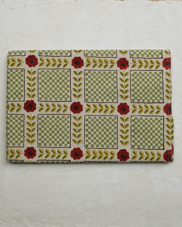 Small rectangular fabric sample with floral and checkered pattern on a textured white background