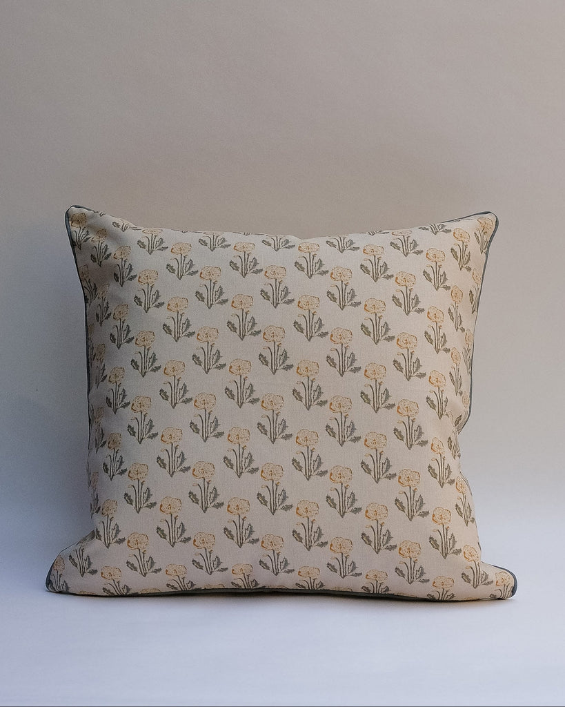 A square decorative outdoor pillow with a retro floral pattern in muted shades of pink, purple, olive green, and beige, finished with dark brown piping.